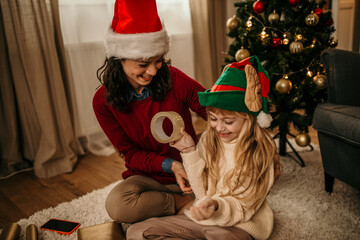 Happy mother and daughter talking while relaxing on Christmas day at home