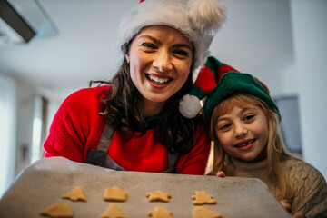 Mother and daughter taking cookies out of the oven at Christmas