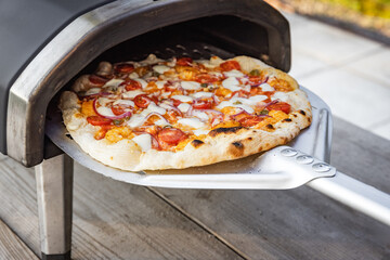 Homemade Pizza close-up. Delicious fresh pizza out of home portable pellets oven. Outdoor pizza...