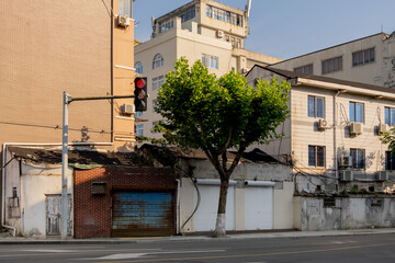 An urban street corner in an Asian country with a traffic light and a mix of older, aging buildings...