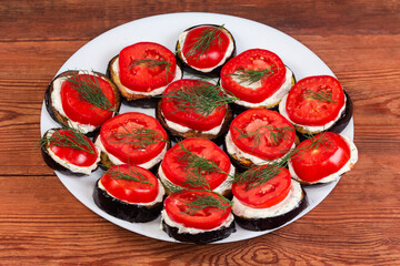 Fried eggplants circles covered with sauce and fresh tomato slices