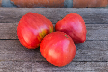 Ripe pink tomatoes on the old rough wooden surface