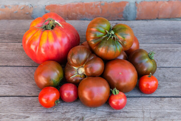 Pink and cherry tomatoes, tomatoes kumato on rough wooden surface
