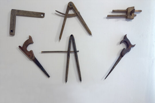 Different old wooden carpenter's gauge tools, crosscut saws on wall