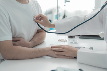 Female doctor uses stethoscope to listen to male patient's heartbeat as a guideline for treatment. Health checkup concept. Close-up.