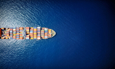 High aerial top down view of a large container cargo ship in motion over open ocean as a banner...