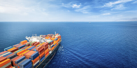 Aerial view of a large, industrial container cargo ship sailing over the ocean with copy space