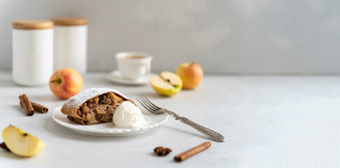 Apfelstrudel, strudel banner. Delicious Freshly baked powdered apple strudel with raisins and ice cream on white plate with red apples and cinnamon on white background. Menu, recipe. Copy space