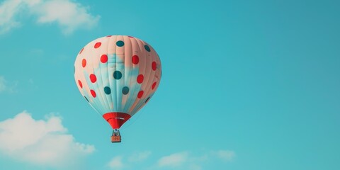 Obraz premium Polka Dot Hot Air Balloon Soaring Against a Blue Sky
