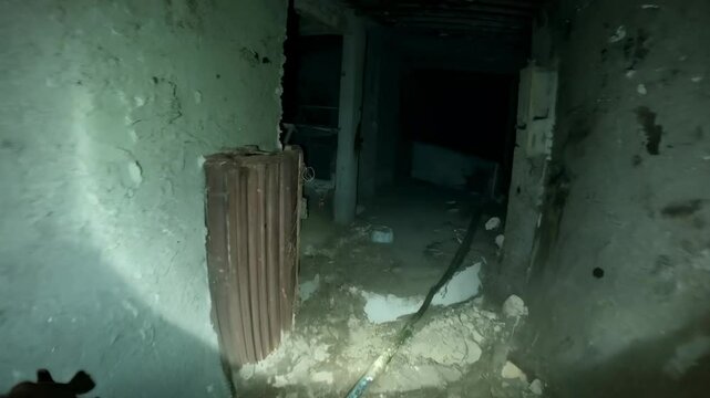 Man is exploring an abandoned building, using a flashlight to see in the dark