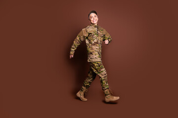 Full body photo of attractive mature woman army soldier walking wear military uniform isolated on brown color background