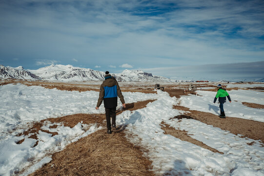 Boys in winter clothing with snow-capped mountains at Ytri Tunga