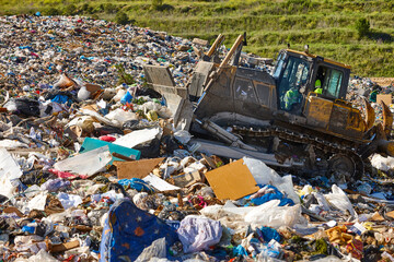 Heavy machinery shredding garbage in an open air landfill. Pollution