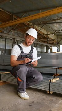 Warehouse worker writes out the invoice before sending metal profile