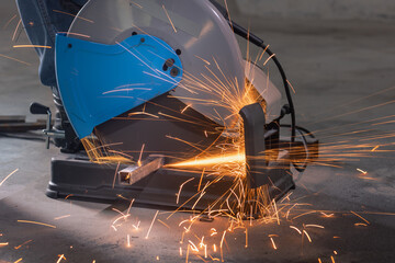 Worker cutting steel rectangular pipe in construction site.