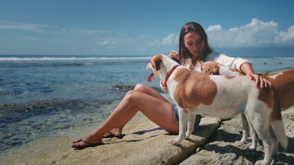 Young woman is enjoying a sunny day at the beach with her three dogs, creating a heartwarming scene of companionship and love for animals