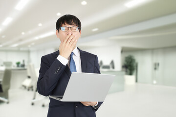 あくびをする寝不足の若いビジネスマン