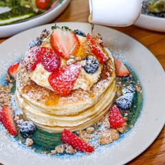 Freshly cooked soft delicious gluten free pancakes stacked on white plate, served with fresh berries, close up. Space for text. Healthy sweet food.