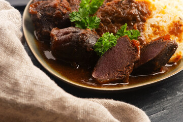 Stewed goose stomach.  Traditional Polish meat on a dark background.