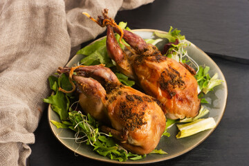 Baked tasty quails on ceramics plate with salad