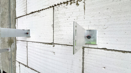 A wall with a white brick wall and a metal bracket. The bracket is attached to the wall and is...