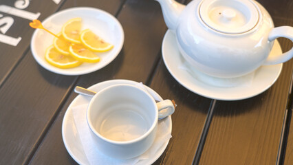 A white tea set with a teapot, a cup, and a plate of lemons