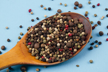 Mix of peppers on a wooden spoon on a blue background