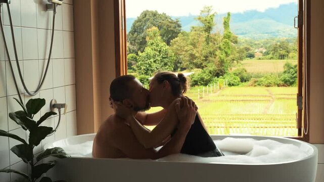 Honeymoon Moments: A Couple Kissing in a Bathtub with a View of Rice Fields in Thailand, Enjoying Love and Relaxation Together