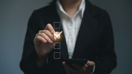 A woman in a business suit is holding a cell phone and drawing a checkmark on virtual checkbox. Concept of professionalism and accomplishment, quality check list business concept.