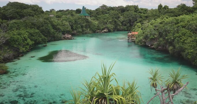 Woman admires a turquoise lake surrounded by lush greenery on sumba island in indonesia, offering a serene and peaceful escape for a relaxing holiday or adventure