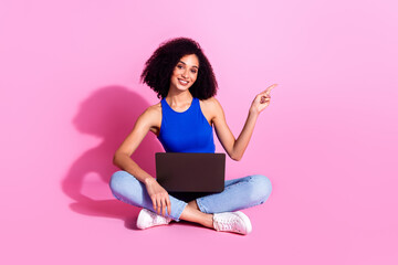 Photo of smiling girl sitting using netbook point finger copyspace isolated pastel color background