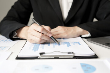 Asian businesswoman sit at their desks and calculate financial graphs showing results about their...