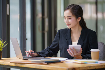 Asian businesswoman using a calculator to calculate work graph business data and analysis.