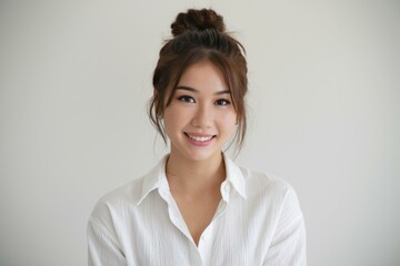 Smiling woman portrait. Young woman in a white shirt, with her hair up, smiling at the camera. Perfect for a business portrait or website.