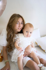 a        photo session on the first birthday of a baby girl with her  teenage sister, in pastel colors, minimalism