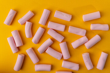 Assorted Marshmallows Randomly Placed on a Yellow Background from a Top-Down Perspective