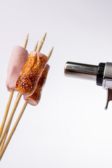 Toasted Marshmallows and Torch in Vertical Composition on White Background