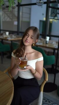 16-year-old teenage girl in old money style clothes drinks bumble coffee with an orange in  fancy restaurant