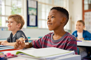Elementary boy in classroom studying with his classmates during lesson