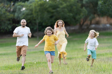 Fototapeta premium Happy family running through grass in the park