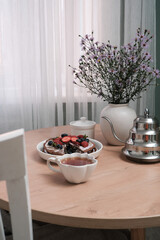 A Beautiful and Delicious Breakfast Setting Featuring Fresh cake with Fruits Accompanied by Flowers in ceramic vase.