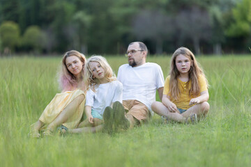 Fototapeta premium Family with two children relaxing on grass in park