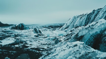 Obraz premium Expansive icy landscape featuring rugged glaciers, deep blue ice, and vast, desolate terrain under a cloudy sky.