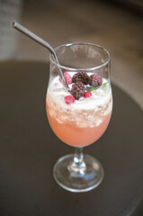 uity cocktail in a tall glass with a glass. Frozen raspberries refresh the drink.