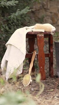 vintage chair outside in garden and towel on tabouret.bath brush and sponge as decoration.