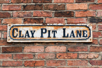 Leeds England: 4th June 2024: A weathered street sign Clay Pit Lane, affixed to an aged brick wall near teh Leeds Arena