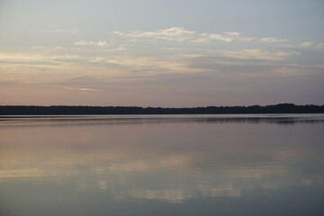 Amazing magical sunset on a forest lake. Quiet evening. Reflection on the surface of the water.