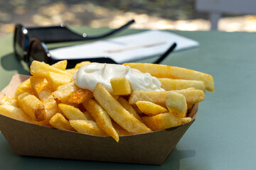 A tray of french fries with a white sauce on top. The fries are golden brown and look delicious