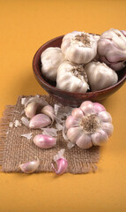 Organic Garlic. Fresh Garlic Cloves and Garlic bulb in wooden basket on yellow background with Pile of garlic or spice. Concept of spices for healthy cooking.