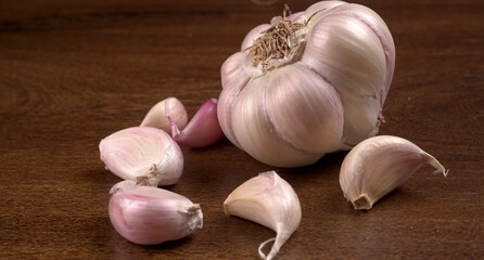 Organic Garlic. Fresh Garlic Cloves and Garlic bulb in wooden basket on yellow background with Pile of garlic or spice. Concept of spices for healthy cooking.